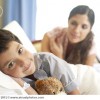 Young boy in hospital bed smiling with woman looking over him